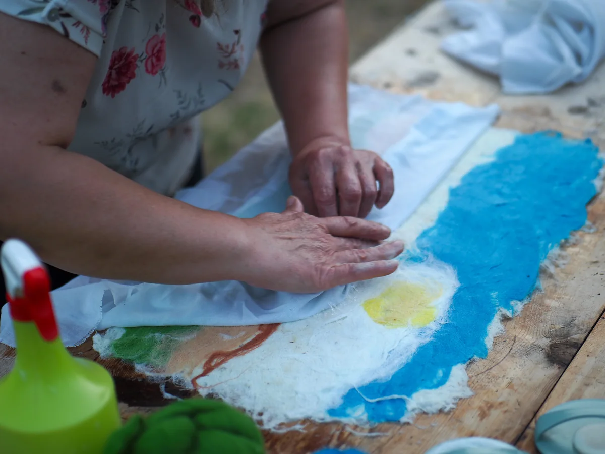 Detalle de las manos frotando la lana húmeda de colores